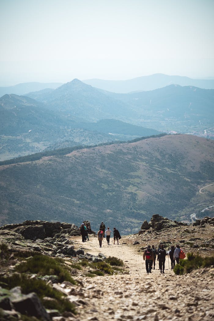 Group of hikers walking on a mountain trail with scenic views in Spain.