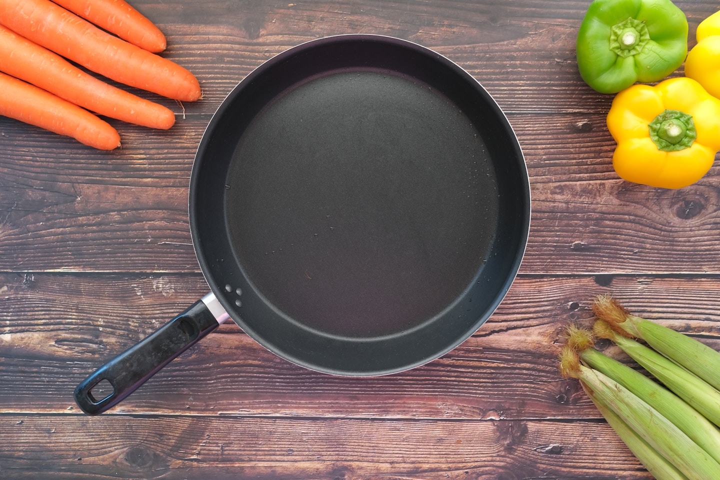 empty frying pan and vegetables on table .