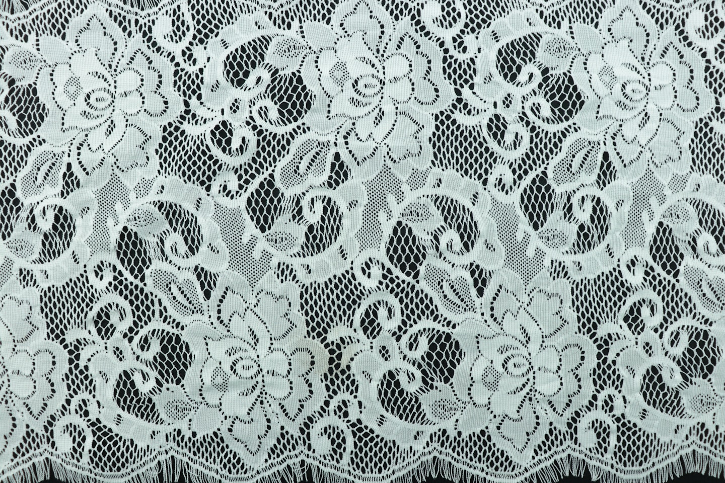 a close up of a white lace on a black background